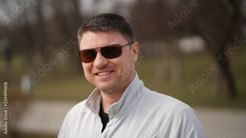 Portrait of a middle-aged smiling man with glasses in a park