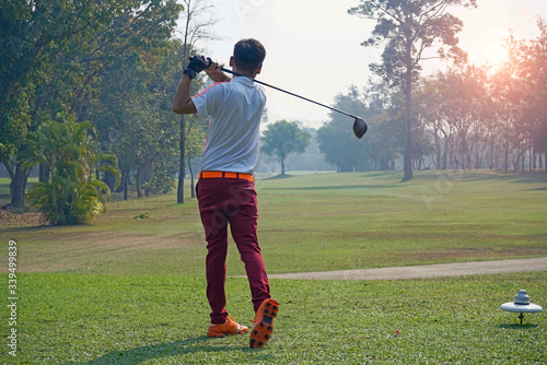 Golfer playing golf in the evening golf course, on sun set evening time.