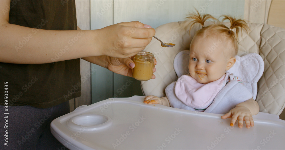 Caucasian mother feeding baby with spoon Caucasian mother feeding baby with spoon