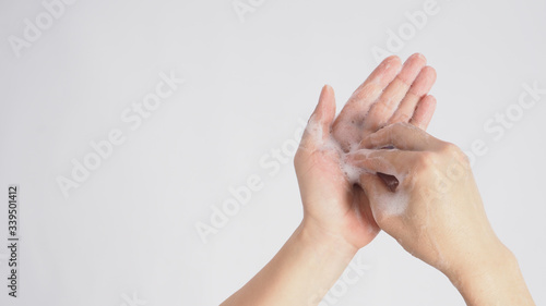 Male model is rub fingertips of one hand on the other plam foaming hand soap on white background.