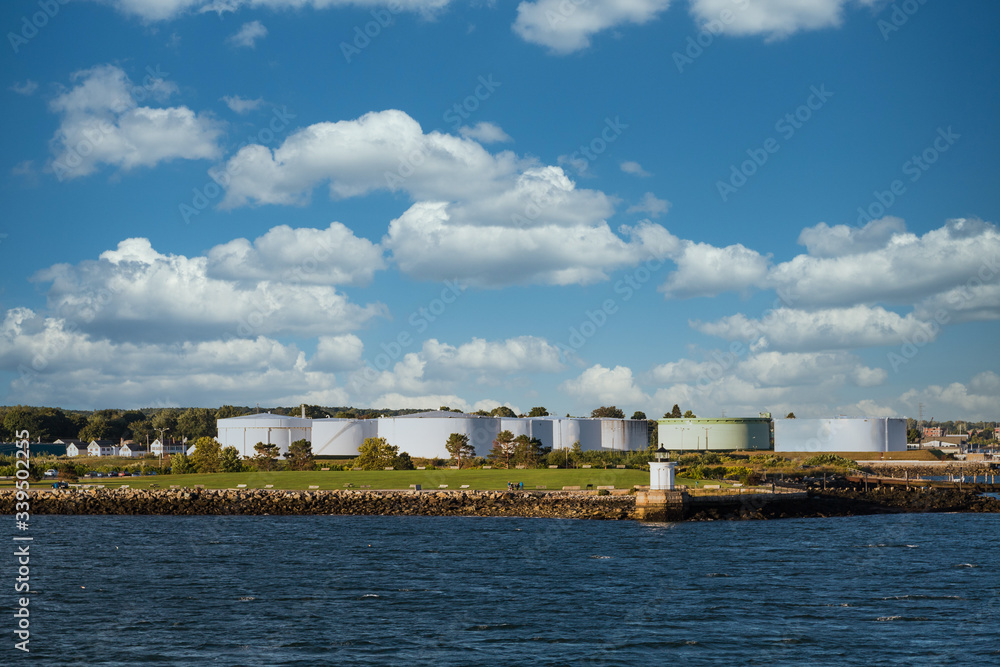 White Fuel tanks on the Canadian coast with a small lighthouse by the water White Fuel tanks on the Canadian coast with a small lighthouse by the water