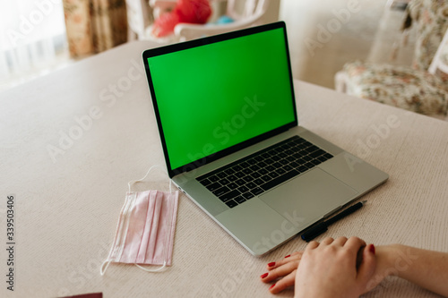 Coronavirus. A medical mask lies near a laptop in the Coronavirus. Medical mask lies near laptop in workplace. Green screen on laptopworkplace.