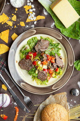 slow cooked pulled beef with fresh vegetable salad close-up on a plate. flat lay, shot from above on a black background