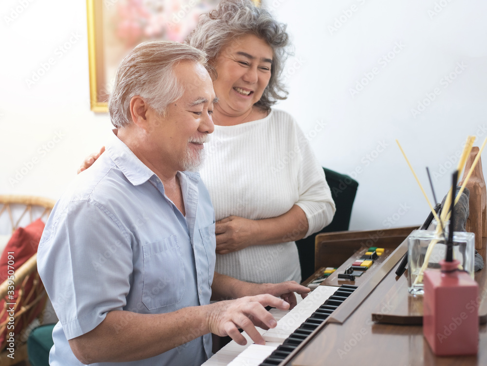 Fototapeta Starszy starszy mężczyzna gra na pianinie w domu opieki, słuchany przez starszą kobietę, Ponowne leczenie starszej azjatyckiej babci i dziadka grają na pianinie w domu z chwilą miłości.