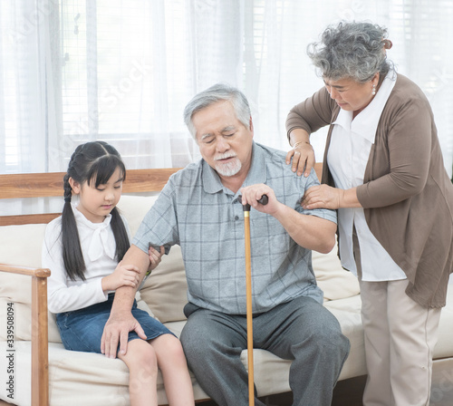 Asian grandfather fall down grandmother and granddaughter help and support carry him to sit on sofa,retirement life concept.