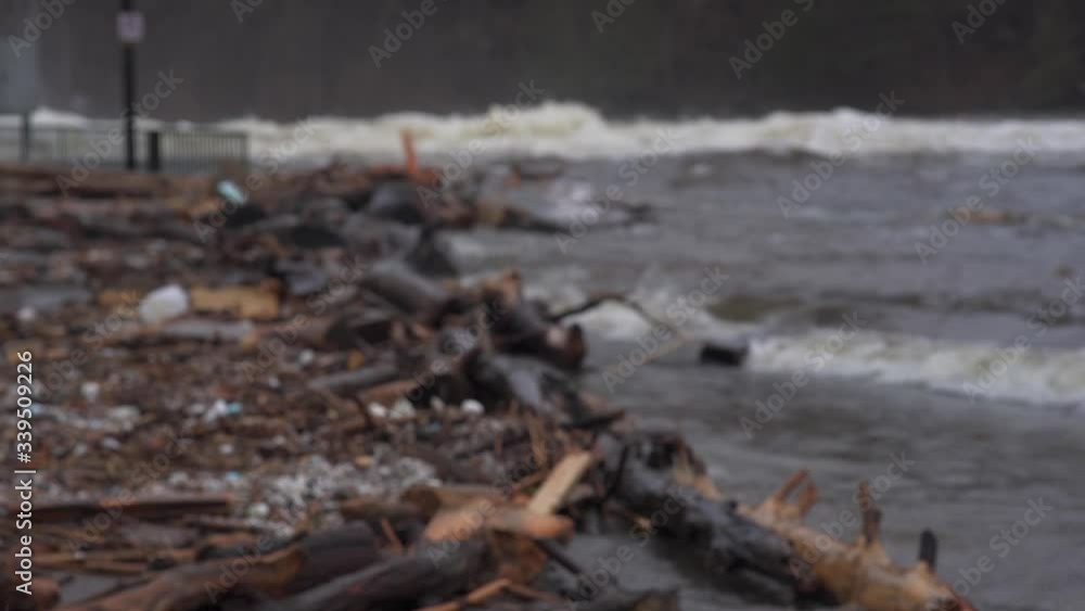 Focus racking shot of Debris scatter along a flooded road and park with violent flood waters in background in Bracebridge Ontario Focus racking shot of Debris scatter along a flooded road and park with violent flood waters in background in Bracebridge Ontario