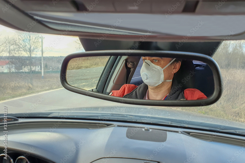 A man drives a car in a protective mask during an epidemic A man drives a car in a protective mask during an epidemic