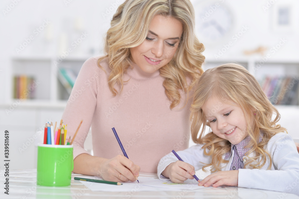Portrait of little cute girl with mother drawing at the table at home Portrait of little cute girl with mother drawing at the table at home