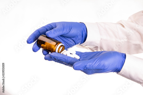 Horizontal view of hands in nitrile protective gloves holding pills.
