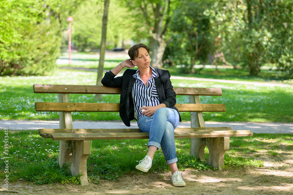 Fototapeta premium Trendy woman relaxing on a rustic park bench