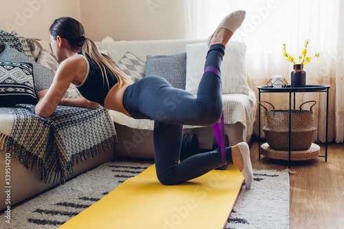 Home workout during coronavirus quarantine. Woman training using mat sport belt. Booty glutes building photo