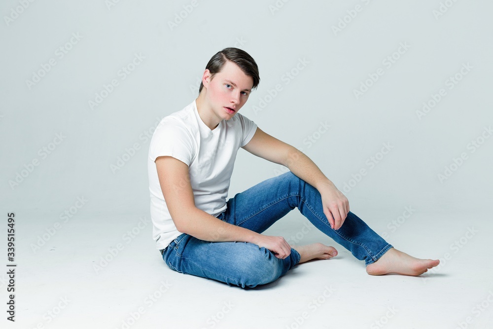 Handsome young man in a white T-shirt and with trendy hairdo on grey background Handsome young man in a white T-shirt and with trendy hairdo on grey background