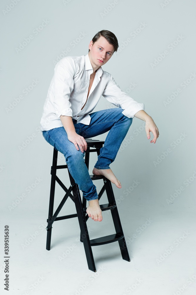 Handsome young man in a white shirt and with trendy hairdo on grey background Handsome young man in a white shirt and with trendy hairdo on grey background