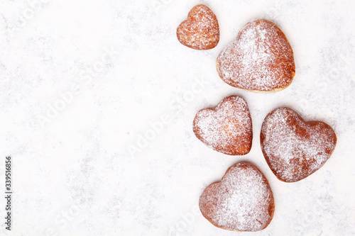 Homemade heart sheped donuts with powdered sugar on white background. Tasty doughnuts, copy space