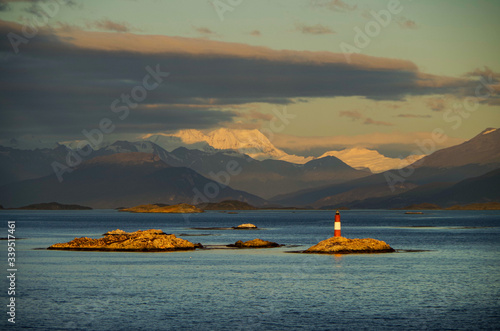 Lighthouse on small rock island in early morning sunlight in Beagle Channel in Patagonia with beautiful nature scenery and landscape during cruise photo