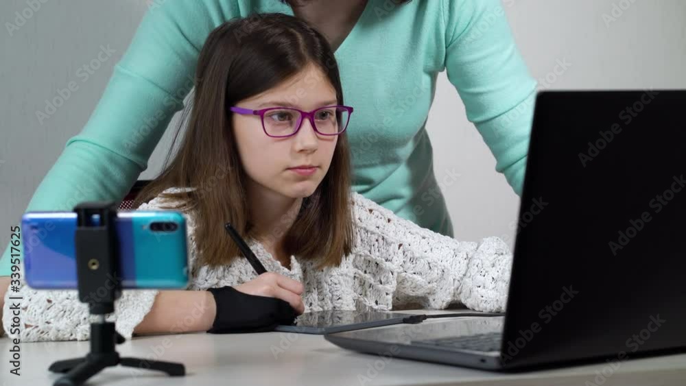 Girl studying graphic design at home and mother assisting her Girl studying graphic design at home and mother assisting her