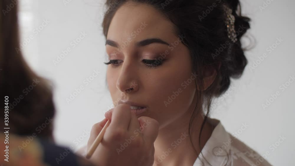 Mixed race bride having her makeup done, specifically her lipstick. Medium-Close shot. Mixed race bride having her makeup done, specifically her lipstick. Medium-Close shot.
