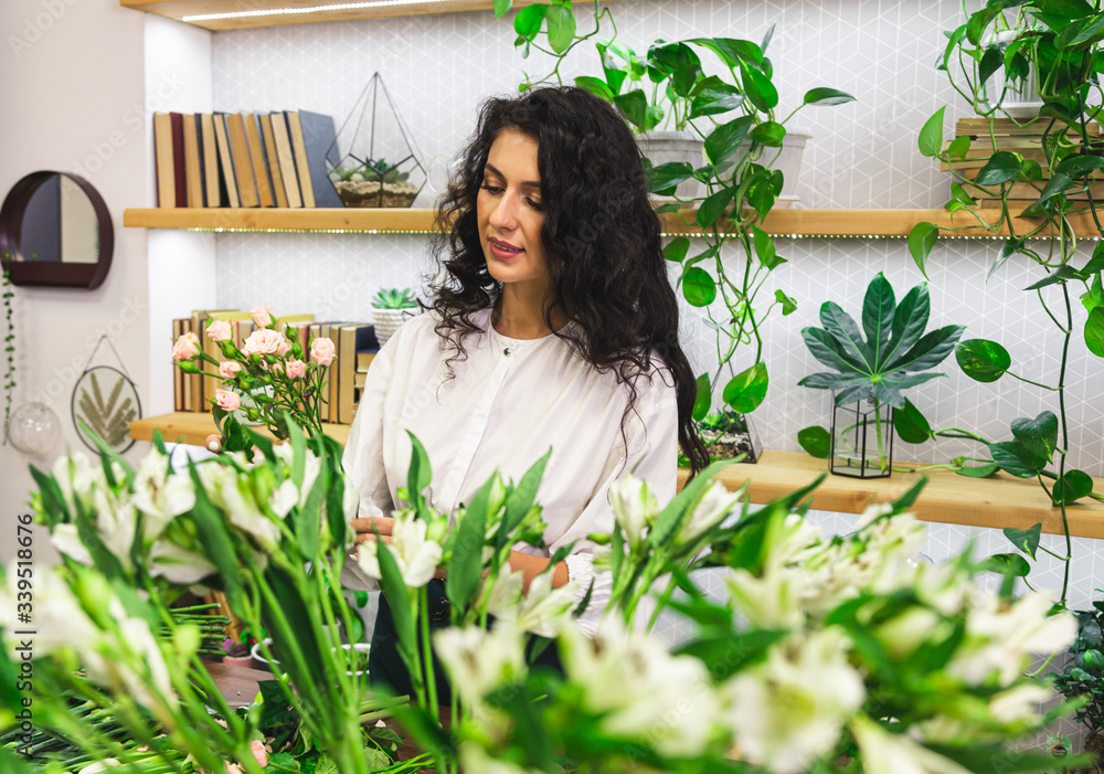 Attractive young woman florist is working in a flower shop. Attractive young woman florist is working in a flower shop.