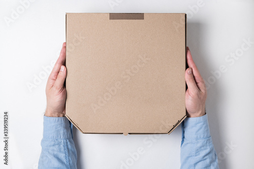 Top view of male hands and box of pizza on white background. Concept of food delivery to home