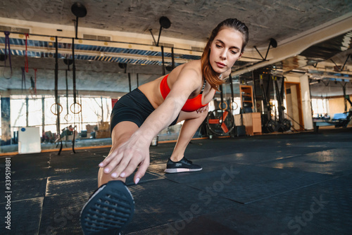 Portrait of athletic sportswoman stretching her leg while working out