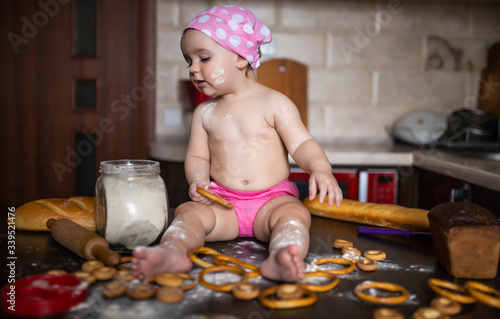 Little girl in the kitchen plays with flour and food.