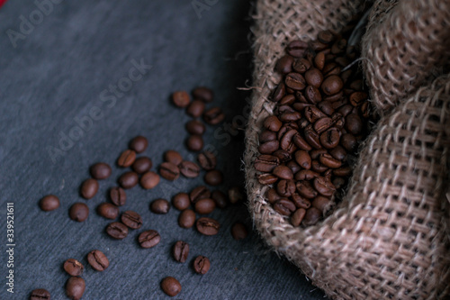 roasted coffee beans in a rough canvas burlap sack on a gray stone buttock. macro closeup view photo