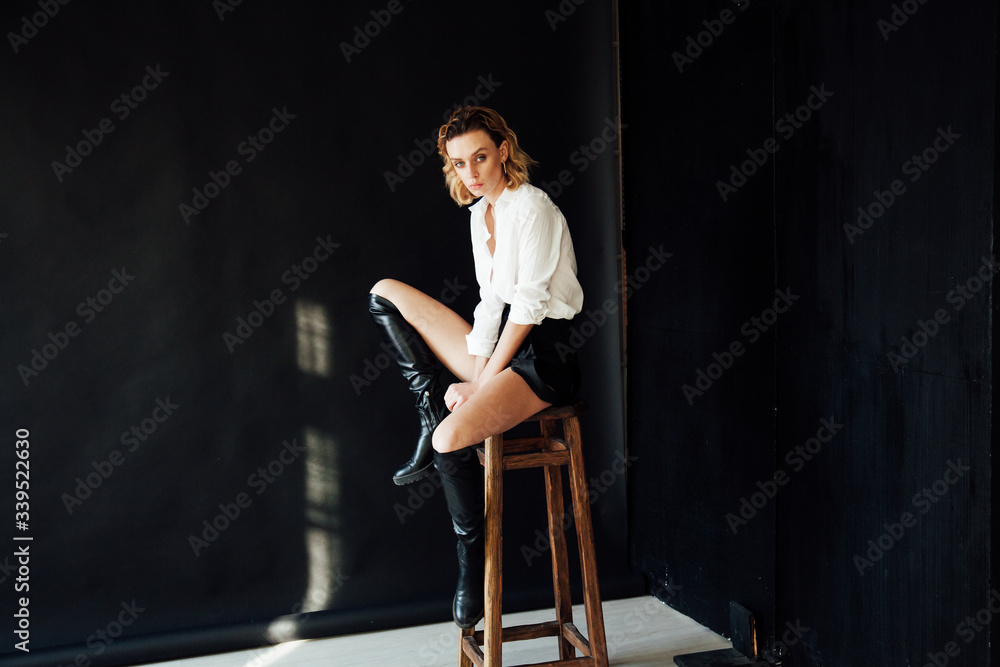 Portrait of a beautiful fashionable blonde woman in black shorts and white shirt