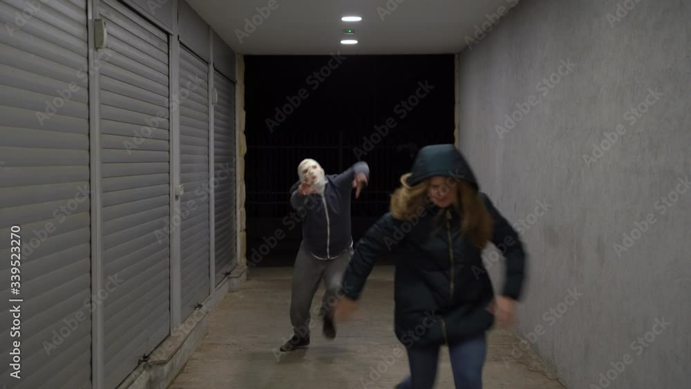 Hungry zombie is chasing from darkness victim down the corridor pedestrian underpass or bunker shelter with flashing light. Blonde girl escapes from walking living dead that wants to eat her brains. Hungry zombie is chasing from darkness victim down the corridor pedestrian underpass or bunker shelter with flashing light. Blonde girl escapes from walking living dead that wants to eat her brains.