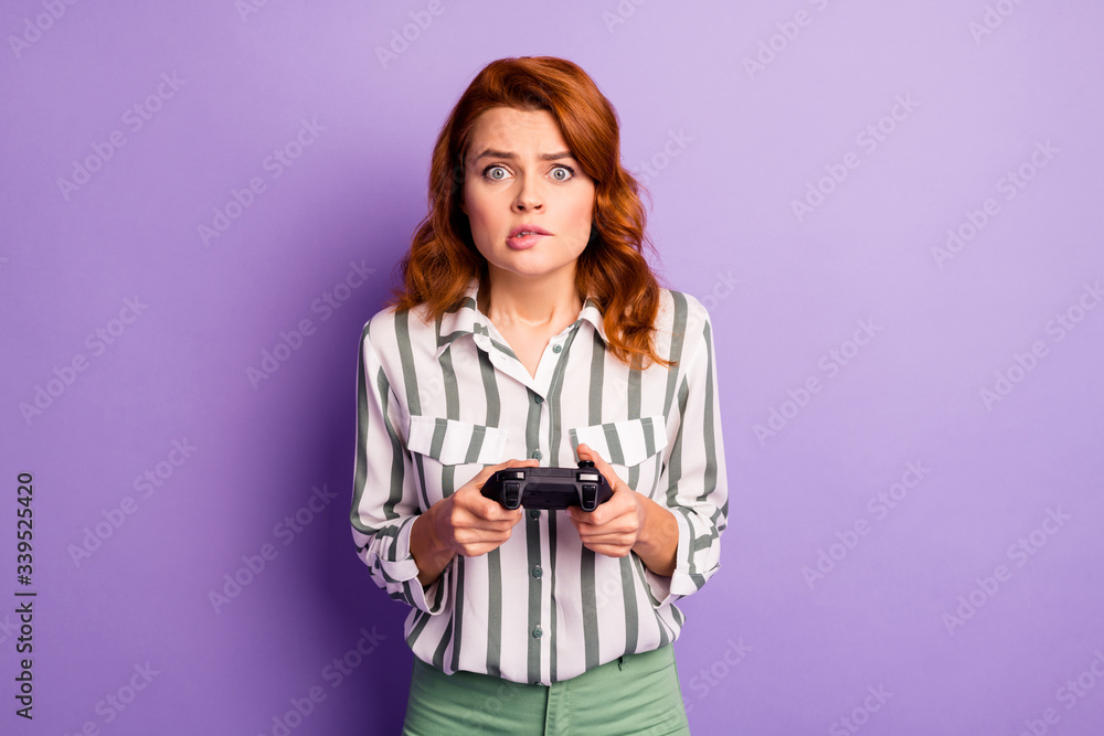 Portrait of anxious crazy woman rest relax play video game lose bite lips hold joy stick wear stylish clothes isolated over violet color background Portrait of anxious crazy woman rest relax play video game lose bite lips hold joy stick wear stylish clothes isolated over violet color background