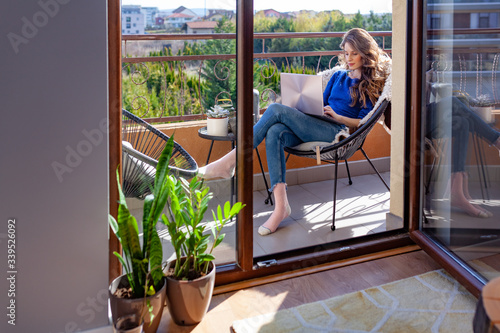 Murais de parede Beautiful young woman working from home on the balcony