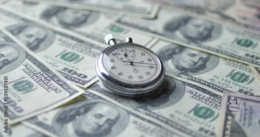The stopwatch lies on the dollars. Time is money concept.