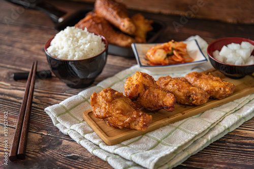 Closed up home made fried chicken with Korean source with garlic, spicy and steamed rice on wooden background, Korean food
