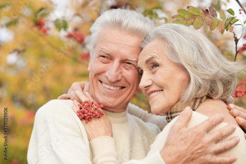 Portrait of beautiful senior couple hugging in the park with rowan berries