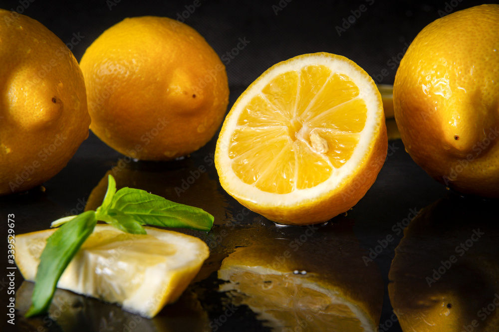 half yellow lemons on a black with reflection , whole citrus, Basil, close up half yellow lemons on a black with reflection , whole citrus, Basil, close up