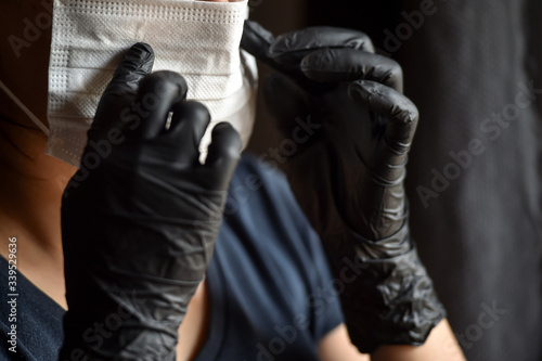 Indoors photo with unrecognizable person wearing black latex medical gloves in times of coronavirus pandemic