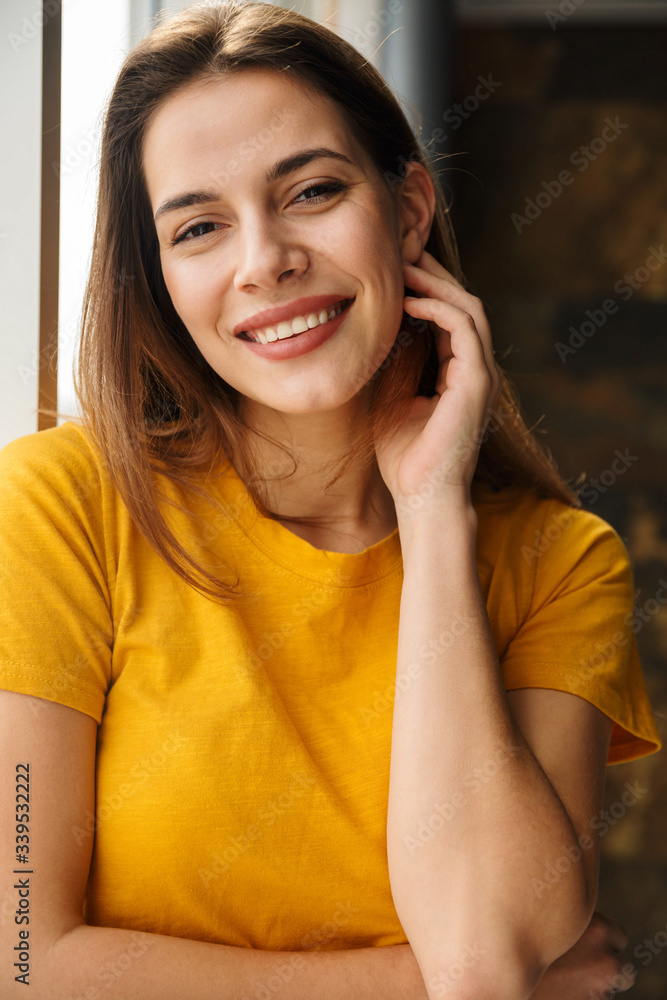 Fototapeta premium Image of pleased woman looking at camera and smiling while standing