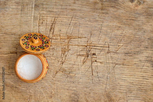 coarse sodium or salt wooden salt shaker on old oak tabletop, close-up, daylight, banner concept, copy space