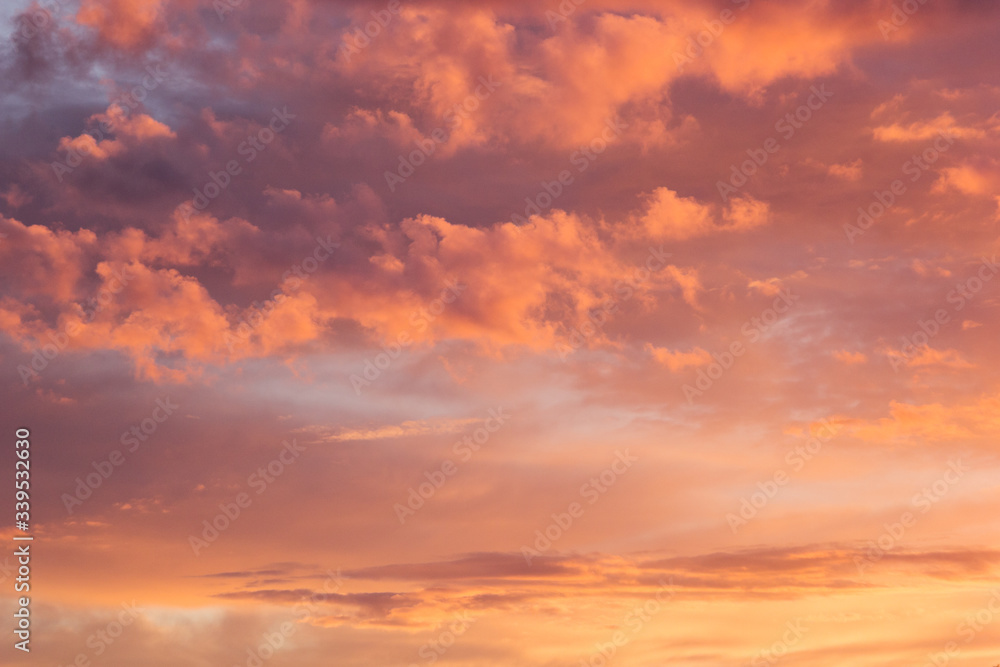Lovely golden and pink clouds in blue heaven with soft haze on sunset as abstract background, texture.