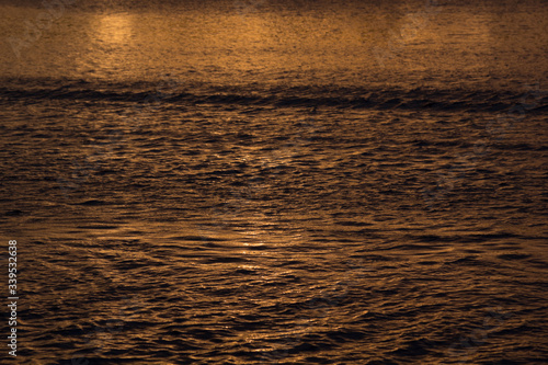Mysterious waves of water in golden sunbeams on sunset, abstract background.