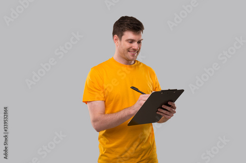 Man Writing in Clip board. Man Holding Clip Board. Man Filling Tax Form. Man Smiling © Alex