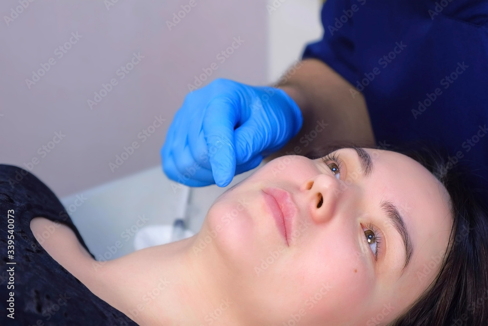 Doctor surgeon checking up woman's moles on face before laser removal, face closeup. Cosmetic treatment in beauty clinic. One day surgery concept. Removing birthmark making surgical procedure.