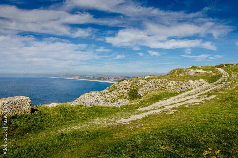 The cliffs of the Jurassic coast on the Isle of Portland, Portland, Dorset, UK on a hazy and sunny Summer morning with Chesil beach in the background