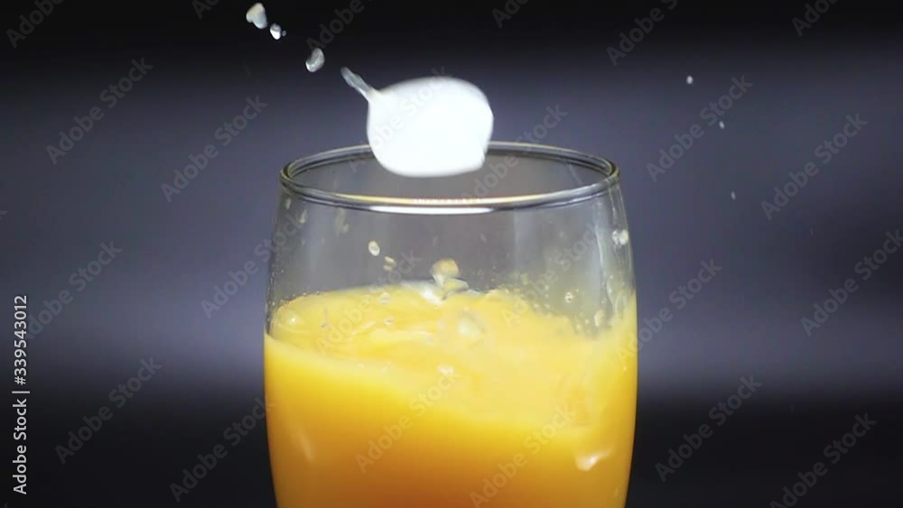 Pieces of ice fall in a glass with orange juice on a black background. Slow Motion 500 FPS Pieces of ice fall in a glass with orange juice on a black background. Slow Motion 500 FPS