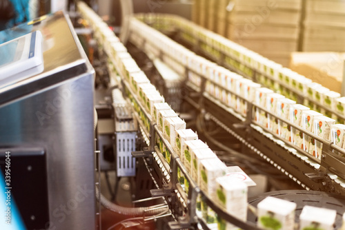 Conveyor with box for juice or water. Conveyor at the plant for the production and bottling of juices in cardboard packaging.