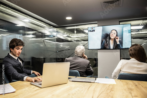 Business partners having video conference in boardroom. Business people looking at monitor screen during video conference in office. Business conference concept photo