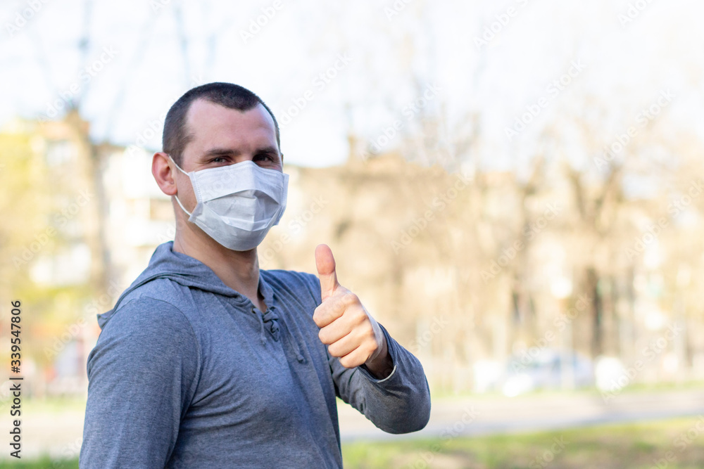 man in protection mask show thumbs up on the street outdoor and looking at camera man in protection mask show thumbs up on the street outdoor and looking at camera