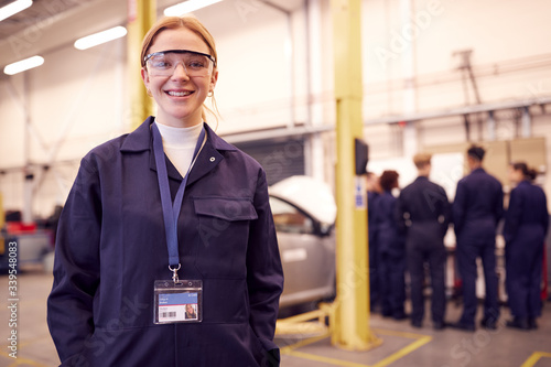 Portrait Of Female Student With Safety Glasses Studying For Auto Mechanic Apprenticeship At College