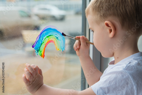  child at home draws a rainbow on the window photo