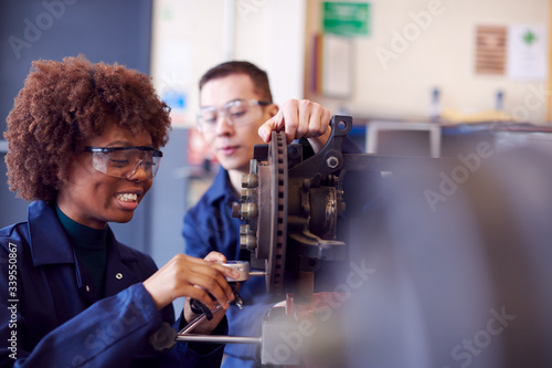 Male And Female Students Working On Car Brakes On Auto Mechanic Apprenticeship Course At College