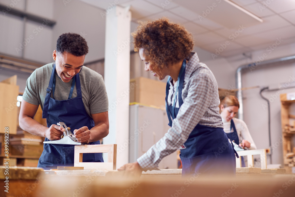 Female Tutor With Carpentry Student In Workshop Studying For Apprenticeship At College Female Tutor With Carpentry Student In Workshop Studying For Apprenticeship At College